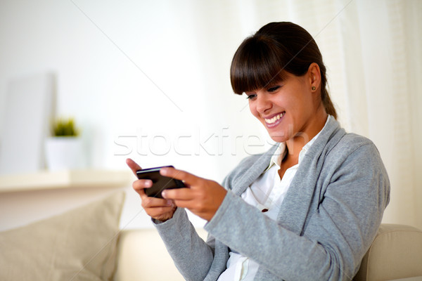 Stock photo: Smiling young woman sending a message by cellphone