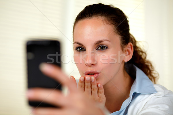 Stock photo: Lovely young woman kissing to cellphone