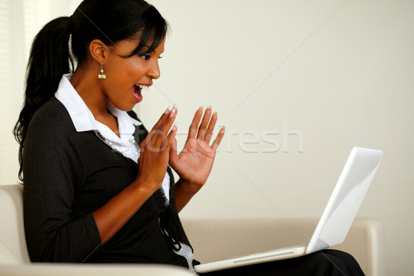 Stock photo: Surprised young woman reading great news on laptop