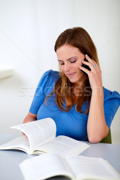 Blonde girl on cellphone while browsing a book Stock photo © pablocalvog