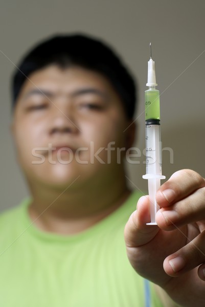 Asian addict holding upright syringe Stock photo © palangsi