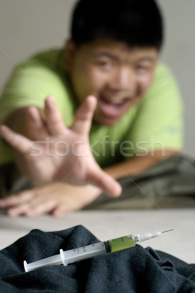 Asian addict reaching for syringe Stock photo © palangsi