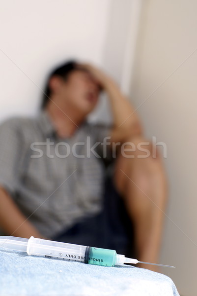 Syringe and sick male addict in corner Stock photo © palangsi