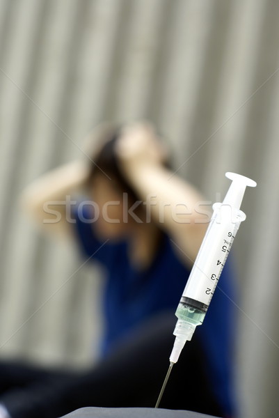 Syringe and female in anguish in the background Stock photo © palangsi