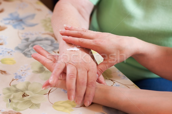 Geriatric nurse anoints elderly woman's hand Stock photo © Pasiphae