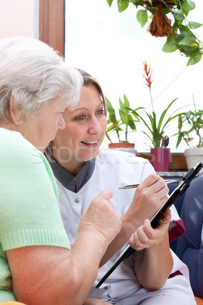 Senior and nurse sit together and write data Stock photo © Pasiphae