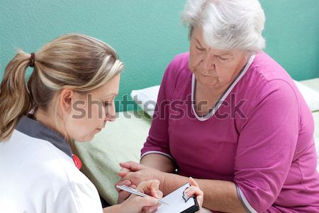 Geriatric nurse cares for elderly woman's arm Stock photo © Pasiphae