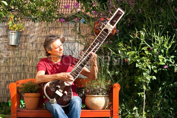 Elderly man sitting in his garden and playing a sitar Stock photo © Pasiphae