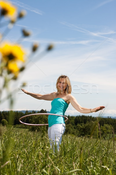 Blond mature woman exercises with hula hoop Stock photo © Pasiphae