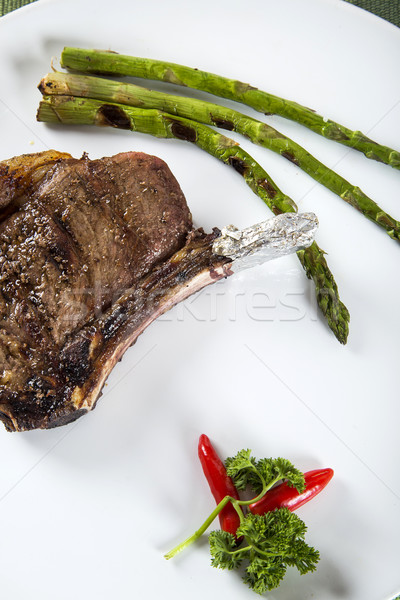 Grilled meat ribs on white plate with tomatoes chives and dark h Stock photo © paulovilela