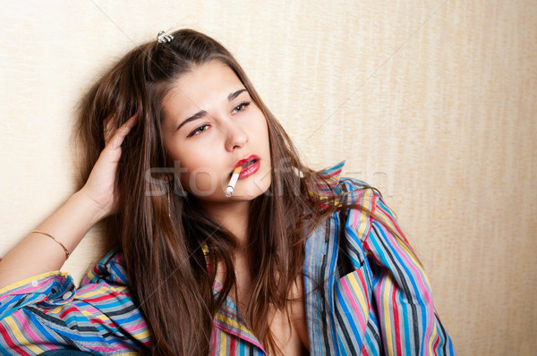 Depressed woman sitting by the wall with cigarette in mouth Stock photo © pekour