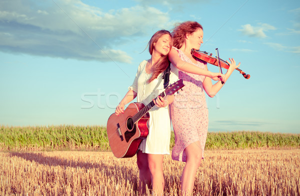 Two young women playing guitar and violin outdoors. Split toning Stock photo © pekour