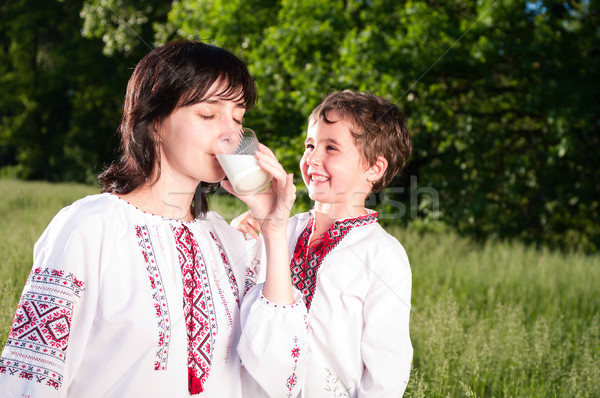 Stock photo: Mother and son in traditional ukrainian shirt drink milk outdoor