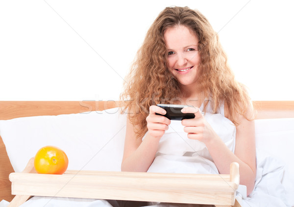 Vrouw video games mobiele telefoon bed geïsoleerd Stockfoto © pekour
