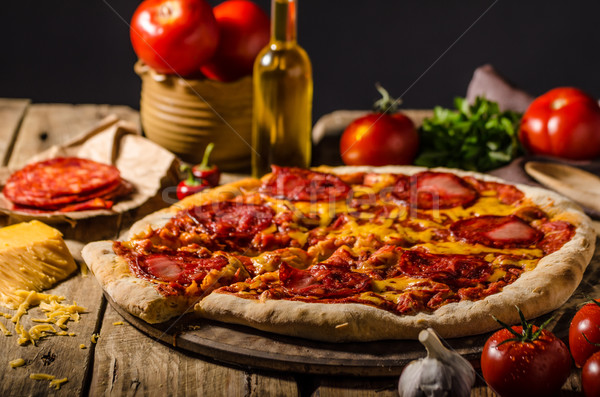 Rustic salami pizza with cheddar cheese and chorizo Stock photo © Peteer