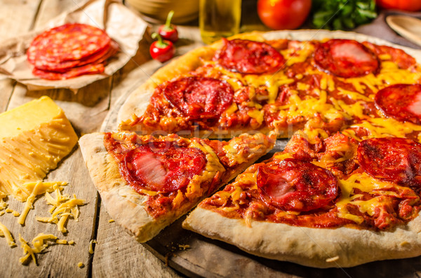 Rustic salami pizza with cheddar cheese and chorizo Stock photo © Peteer