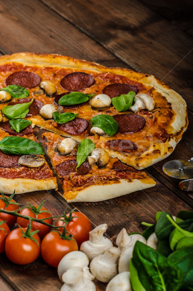 Rustic pizza with salami, mozzarella and spinach Stock photo © Peteer
