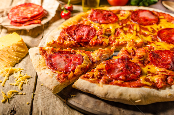 Rustic salami pizza with cheddar cheese and chorizo Stock photo © Peteer