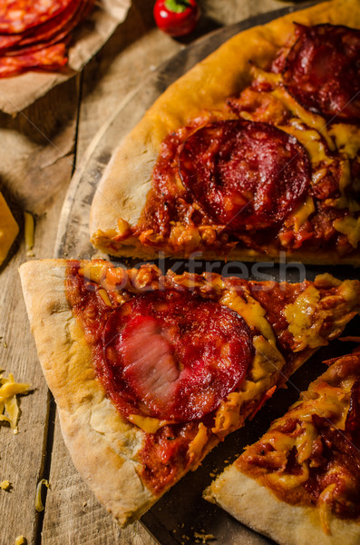 Rustic salami pizza with cheddar cheese and chorizo Stock photo © Peteer