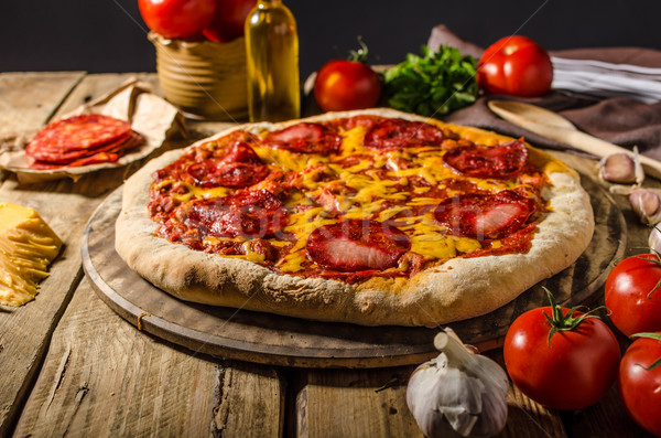 Rustic salami pizza with cheddar cheese and chorizo Stock photo © Peteer