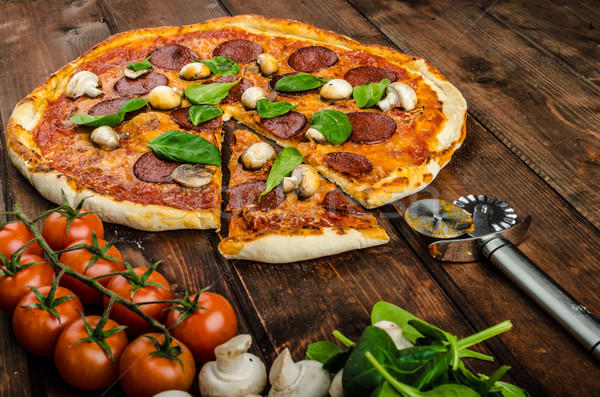 Rustic pizza with salami, mozzarella and spinach Stock photo © Peteer