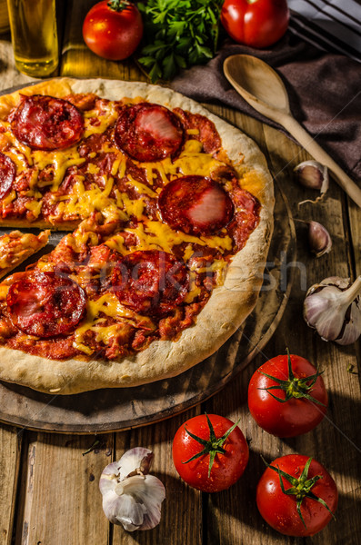 Rustic salami pizza with cheddar cheese and chorizo Stock photo © Peteer