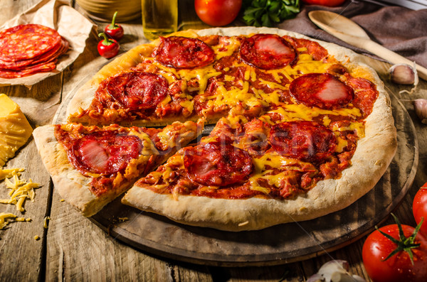 Rustic salami pizza with cheddar cheese and chorizo Stock photo © Peteer