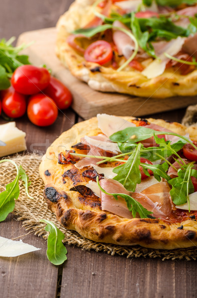 Italian pizza with parmesan cheese, prosciutto and arugula Stock photo © Peteer
