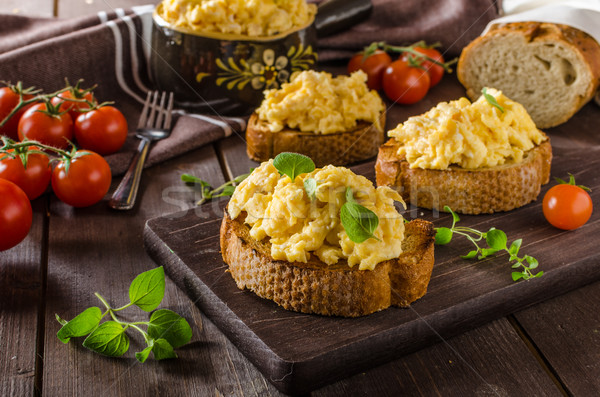 Stock photo: Scrambled eggs with herbs and garlic on toasted bread