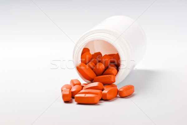 Stock photo: orange pills spilling from bottle