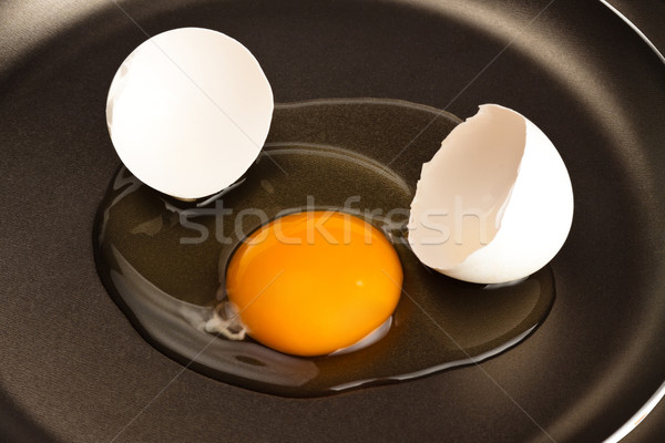 broken egg on black pan Stock photo © PetrMalyshev