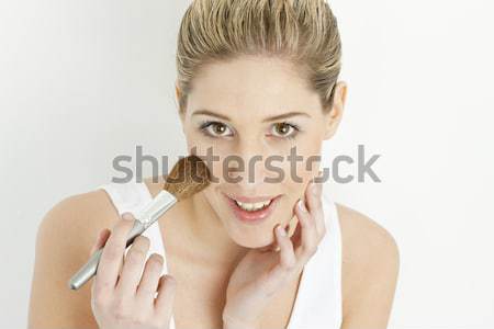 portrait of young woman putting on face powder Stock photo © phbcz