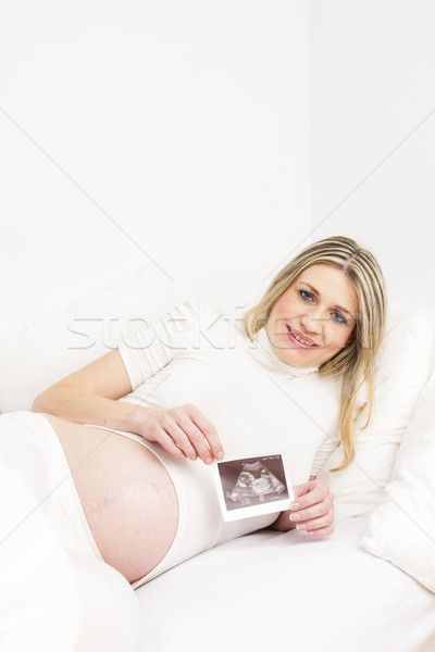 pregnant woman resting in bed with a sonogram of her baby Stock photo © phbcz