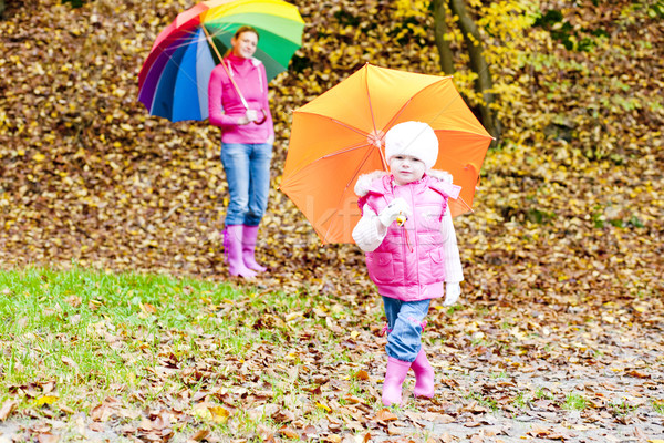 Stock photo: mother and her daughter with umbrellas in autumnal nature