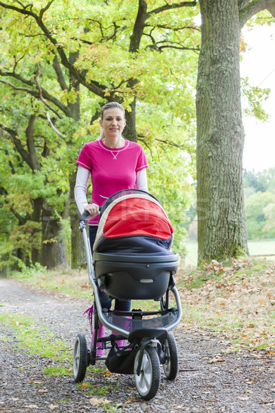 woman with a pram on walk in autumnal alley Stock photo © phbcz