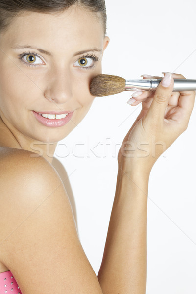 portrait of young woman putting on face powder Stock photo © phbcz