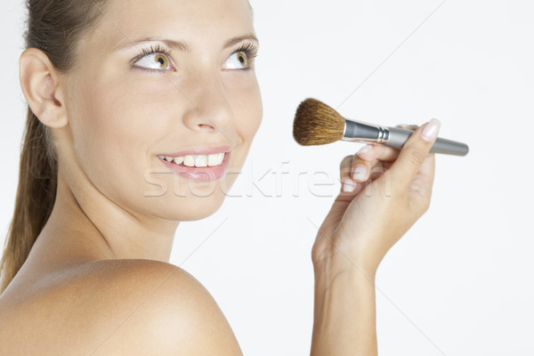 portrait of young woman putting on face powder Stock photo © phbcz