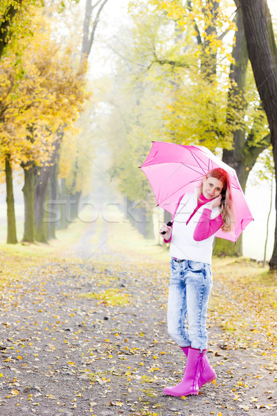woman wearing rubber boots with umbrella in autumnal alley Stock photo © phbcz