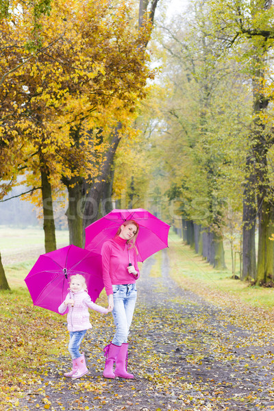 Stock photo: mother and her daughter with umbrellas in autumnal alley