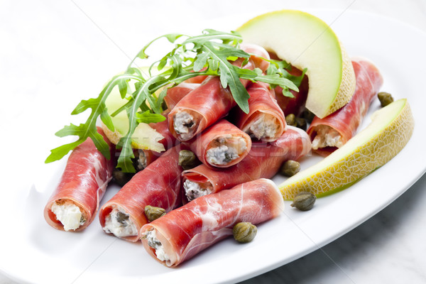 Stock photo: Parma ham rolls filled with cream cheese, Galia melon and capers