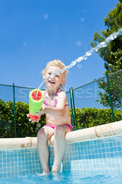 little girl with water sprayer by swimming pool Stock photo © phbcz