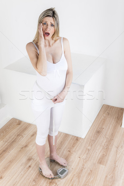 pregnant woman standing on a weight scale with a tape measure Stock photo © phbcz
