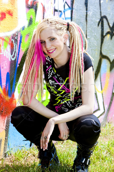 Stock photo: young woman sitting at graffitti wall