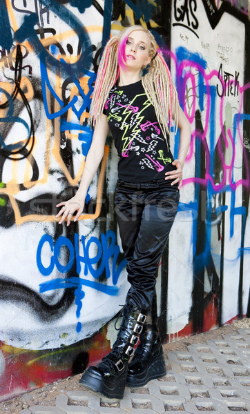 young woman standing at graffitti wall Stock photo © phbcz