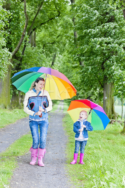 Stock photo: mother and her daughter with umbrellas in spring alley