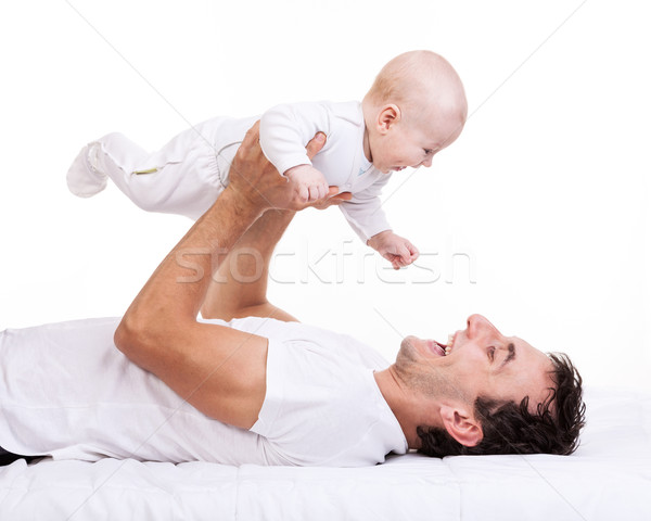 Young man holding baby son while lying on back Stock photo © photobac