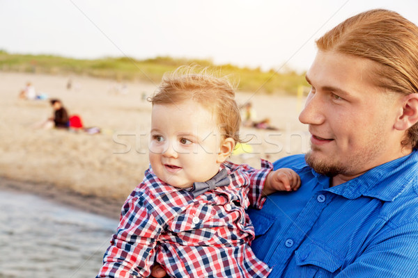 Stock photo: Young father holding his child on the beach having fun together.