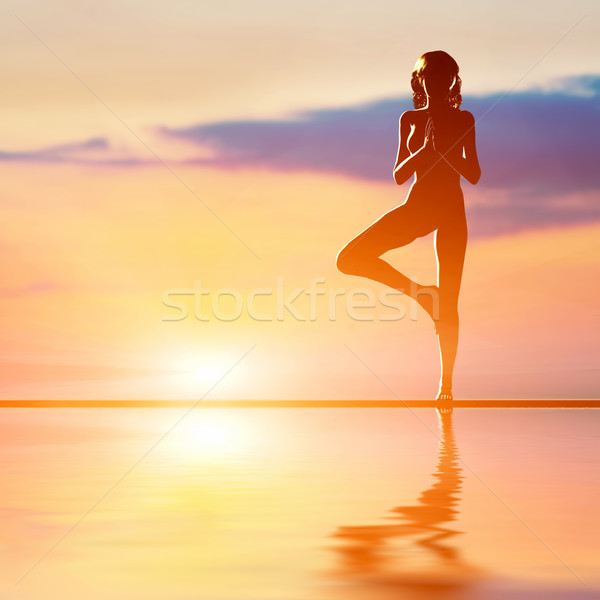 A silhouette of a woman standing in tree yoga position, meditating against sunset sky Stock photo © photocreo