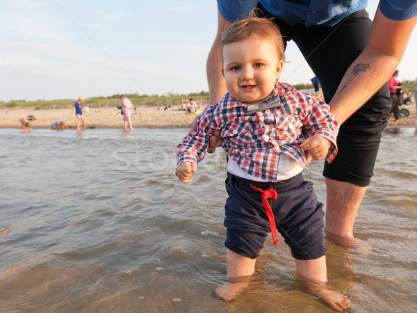 Young father holding his child over sea water having fun together. Stock photo © photocreo