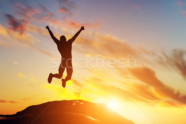 Happy man jumping for joy on the peak of the mountain at sunset. Success Stock photo © photocreo